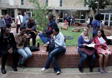 Students chat outside lecture halls at the University of the Free State in Bloemfontein, South Africa. Races are mixing more but often they socialize with their own kind.