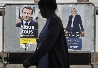 A pedestrian walks past campaign posters of French President and La Republique en Marche (LREM) party candidate for re-election Emmanuel Macron (L) and French far-right party Rassemblement National (RN) presidential candidate Marine Le Pen in Mulhouse
