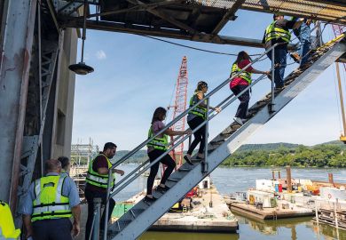 People climb up to the dam during a tour of Montgomery Locks and Dam on the Ohio River in Monaca, Pennsylvania to illustrate National Institutes of Health weighs pay hike for postdocs