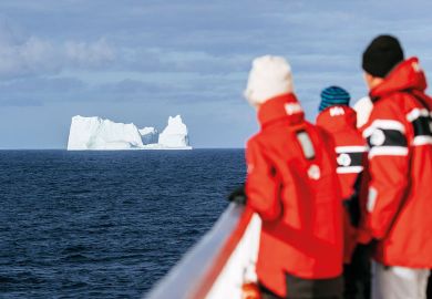 People looking at an iceberg in the distance to illustrate Icebergs, straight ahead