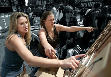 Two ladies pointing at a giant Sudoku in the street as a metaphor for problem solving.