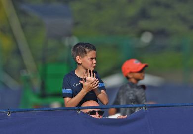 A tennis fan watches a game on his father shoulders over the fence n Surbiton, England to illustrate Reverse visa crackdown for ‘brightest and best’, says LBS dean