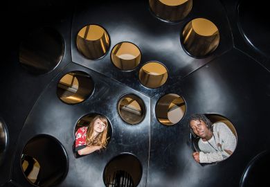 Two people looking inside holes in an immersive art installation in London, UK Two people looking inside holes in an immersive art installation in London, UK_to illustrate Academics urged to fill policy void at heart of new UK government