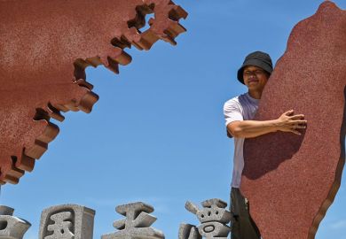 A tourist poses with a monument representing mainland China to illustrate Taiwan-Beijing tensions ‘could rattle international students’