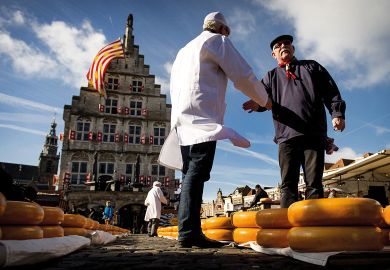 Shaking hands with a Cheesemaker at a market at the opening of the Dutch Cheese season in Goudato illustrate UK universities near Elsevier deal after publisher drops price