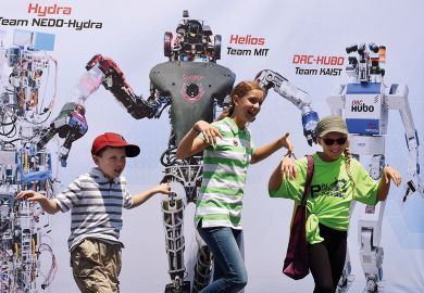 Children pose in front of a promotional poster during the finals of the DARPA Robotics Challenge Children pose in front of a promotional poster during the finals of the DARPA Robotics Challenge to illustrate Canada joining the rush to create a Darpa