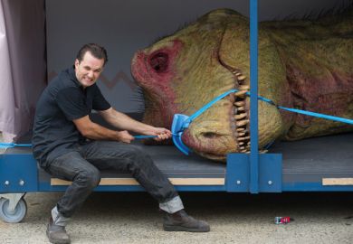 Staff ties a model T-Rex dinosaur around it's mouth to illustrate Student debt  starts to bite  in Australia