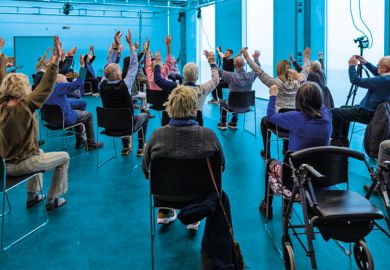 Group sitting with hands up doing exercises