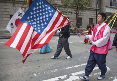 Annual Korean Day Parade man holding American flag to illustrate ‘High stakes’ and hurdles ahead for KAIST’s New York campus