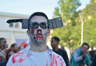 Bristol Zombie walk, man with fake axe over his head to illustrate Universities alarmed as ‘bloody’ budget set to hike staff costs