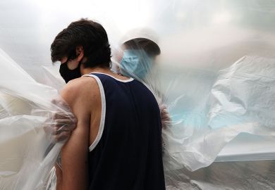 John Sileo hugs his grandfather, Domenik Sileo through a plastic drop cloth hung up on a homemade clothes line during Memorial Day Weekend on May 24, 2020 in Wantagh, New York.