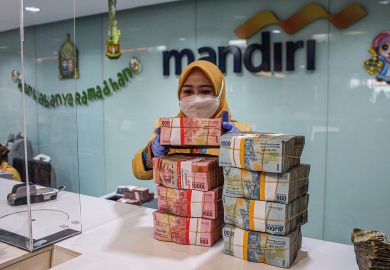 A woman arranges bundles of Indonesian rupiah banknotes at Mandiri Mikro Business Unit Bandung Braga in Bandung A woman arranges bundles of Indonesian rupiah banknotes at Mandiri Mikro Business Unit Bandung Braga in Bandung to illustrate South-east Asian currency slide could hit student mobility
