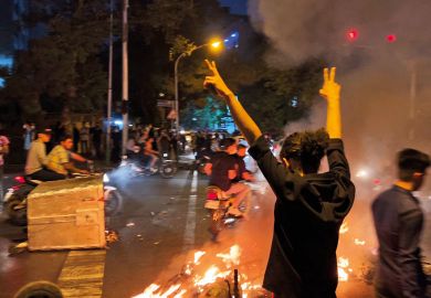 A demonstrator raising his arms and makes the victory sign during a protest for Mahsa Amini to illustrate Academics under mounting pressure to join Iranian protests