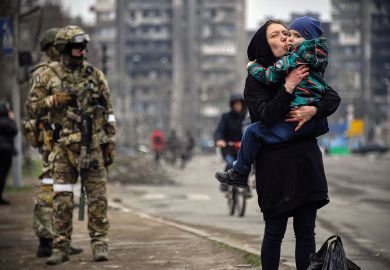 A woman holds and kisses a child next to a Russian soldier A woman holds and kisses a child next to a Russian soldier to illustrate Upsurge in defence research awakens disciplinary divisions