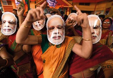Supporters wearing masks of Indian Prime Minister Narendra Modi dance as they celebrate on the vote results day for India's general election to illustrate Academic walkout raises questions about university thinktanks