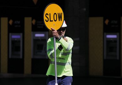 A traffic control worker holds a traffic sign reading "Slow" in Brisbane, Australia to illustrate Visa chaos ‘latest driver’ of ‘two-tiered Australian sector’
