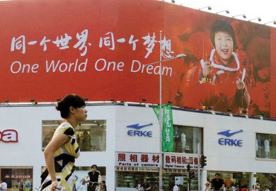 Person walking past a poster reading 'One World One Dream' in English and Chinese. Person walking past a poster reading 'One World One Dream' in English and Chinese as a metaphor for Taiwan eyes international recruitment with switch to English.