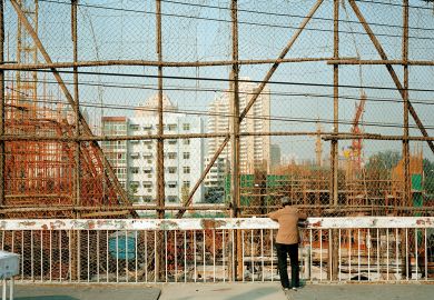Woman looking down at construction site, Beijing, China to illustrate Chinese universities abandon or repurpose regional campuses