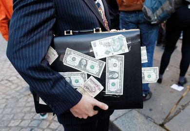 A protester dressed as a businessman, holds a briefcase covered in U.S. dollar notes to illustrate Stanford law school trials income-based student loans