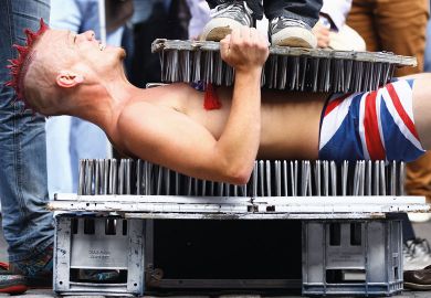 A Street entertainer lays down on a bed of nails to illustrate Next generation of humanities scholars ‘imperilled’ by PhD cuts