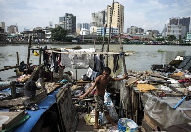 Worker collecting plastic bottles floating on the river at the banks of Pasig River in Manila Worker collecting plastic bottles floating on the river at the banks of Pasig River in Manila to illustrate Philippines’ higher education ‘more unequal despite reforms’