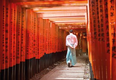Monk walking in Fushimi inari shrine path of torii, Kyoto, Japan to illustrate Japan expected to lose 140,000 students by mid-century