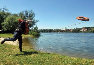A rescuer throws a lifebelt into a lake