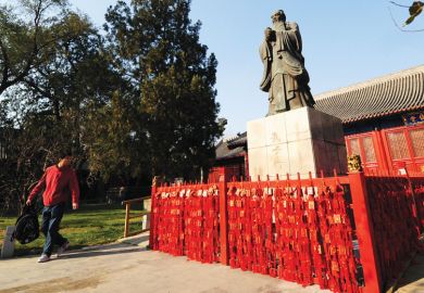 A man walking past looks at a statue of Chinese philosopher Confucius A man walking past looks at a statue of Chinese philosopher Confucius