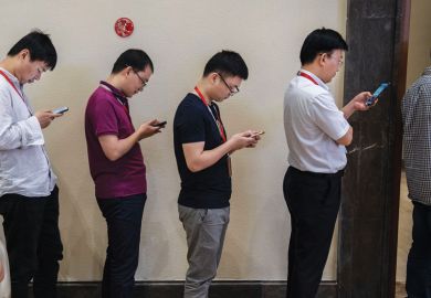 row of men  look at their smartphones 