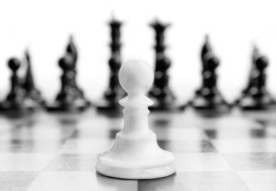 White chess pawn in foreground ahead of black pieces