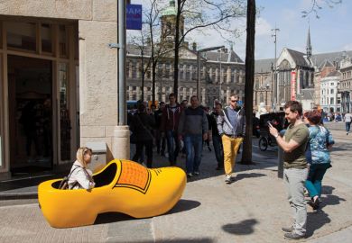 Woman sitting in giant yellow clog Woman sitting in giant yellow clog