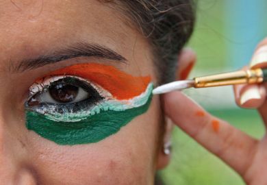 Woman painting eyes in colours of flag of India