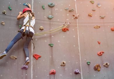 Woman representing a PhD student climbing in an indoor climbing centre
