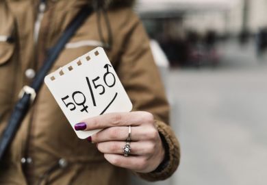 Woman holding up 50 50 gender sign