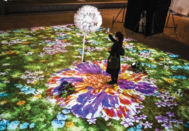 A woman uses her smartphone in an interactive multimedia installation that connects Singapore and Japan in a time of separation, in Tokyo on November 13, 2020