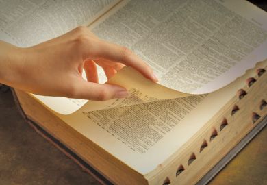Woman's hand turning dictionary pages