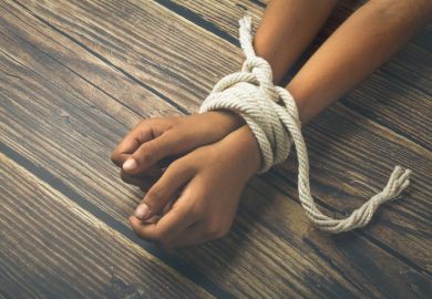 A person's wrists bound with a rope, symbolising the restriction of academic freedom