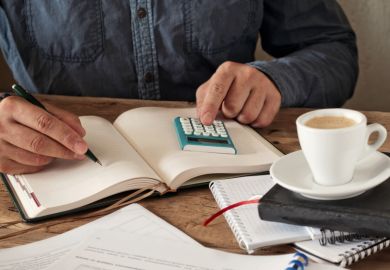 Man writing in a diary with calculator