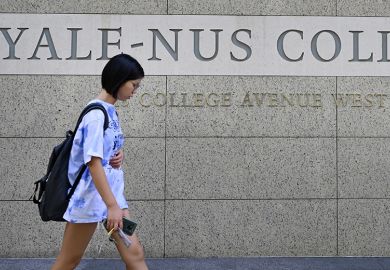 A student walking past signage for the Yale-NUS College in Singapore