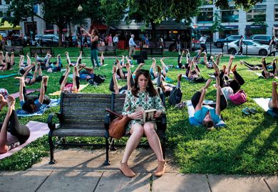 Woman on bench with outdoor yoga class behind her, illustrating lifelong learning