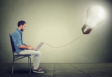 Young male entrepreneur using laptop, lightbulb, Eureka