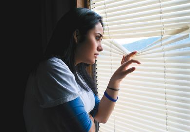 Young woman peeking through venetian blinds Young woman peeking through venetian blinds
