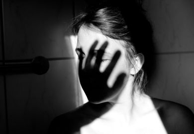 Young woman with shadow of hand over face