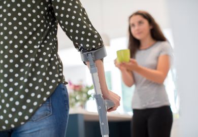 A young carer makes a drink for her disabled parent
