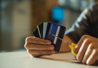 Young man cutting credit card with scissors