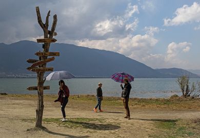 Tourists with umbrellas at Erhai Lake in Xizhou, China