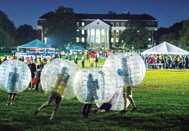 People in plastic bubbles play on a field People in plastic bubbles play on a field