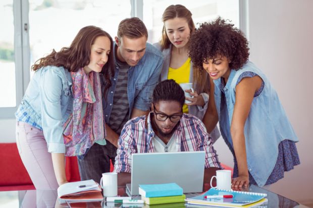 A group of students gathered around a laptop A group of students gathered around a laptop