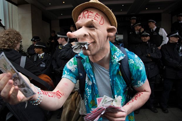 A protester wearing a greed mask holding fake money
