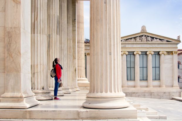 A girl looks up at the ceiling, under the columns of the Athenian Academy